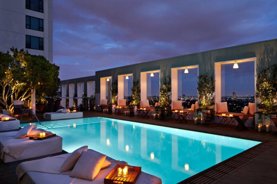 Rooftop pool at night time with cabanas and loungers with small candles throughout