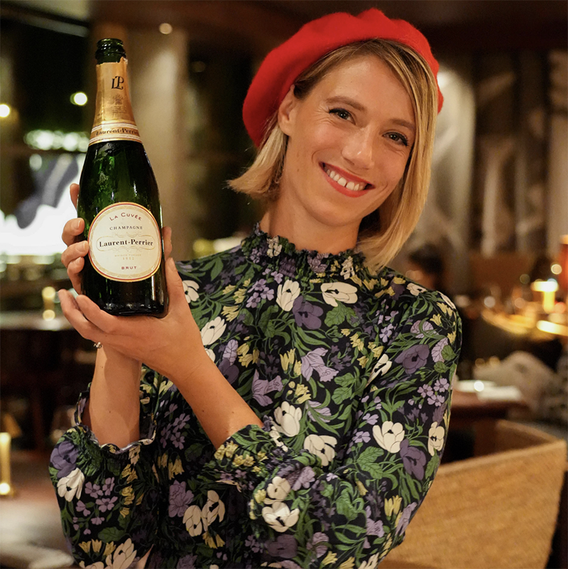 Woman holding bottle of champagne in red beret