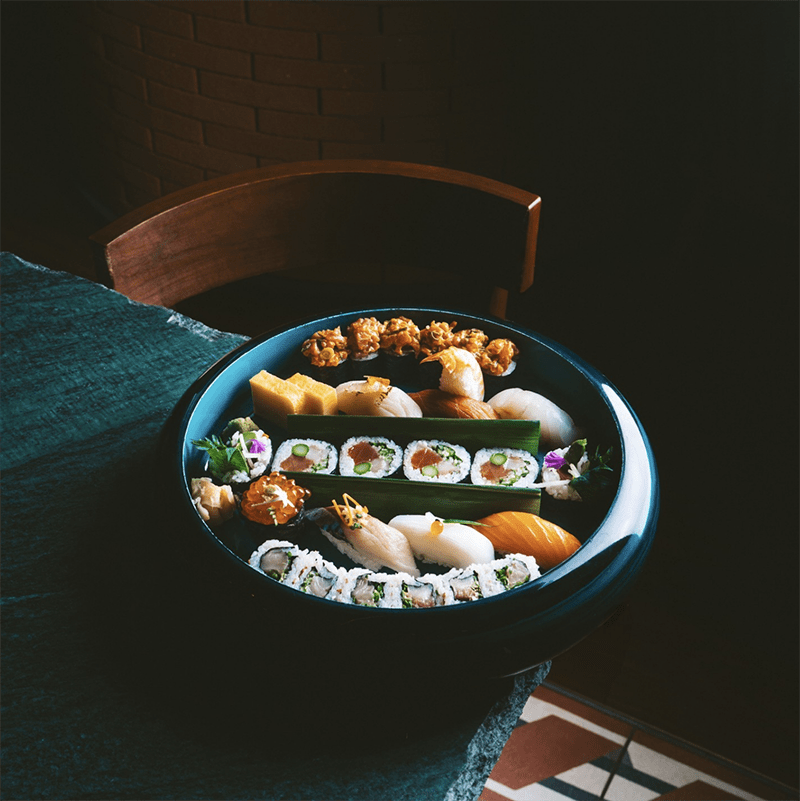 Sushi on a black plate on a dark wooden table