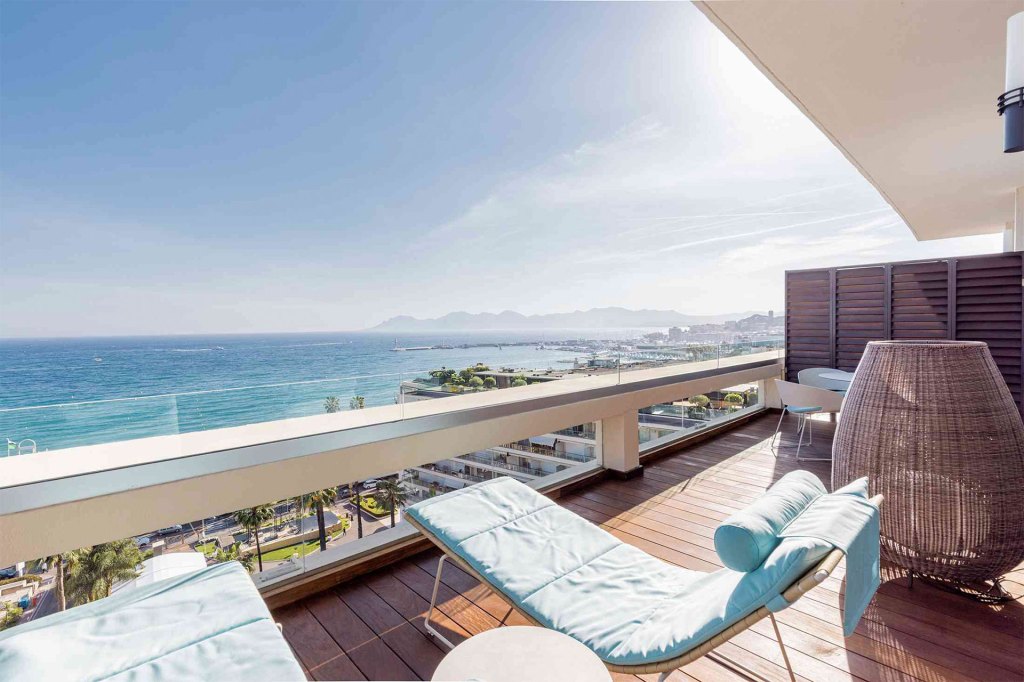 Une vue calme sur la mer depuis un balcon avec des chaises longues confortables.