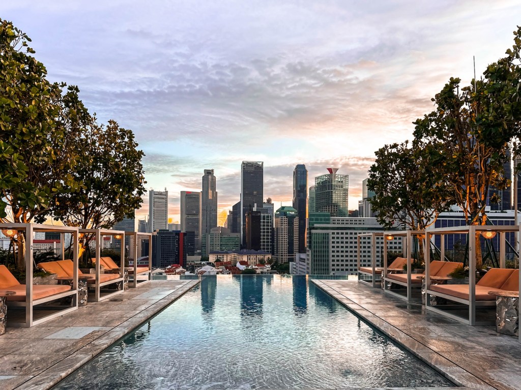 Rooftop pool with cabanas on the sides and a skyline in the background