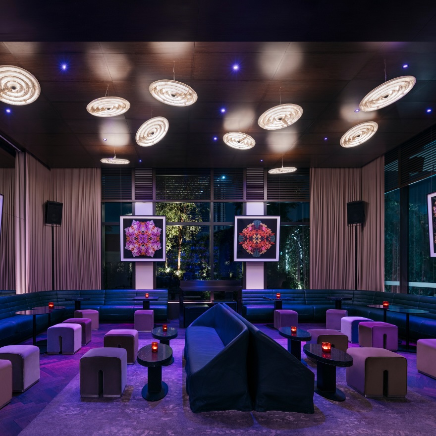 Stylish lounge/bar with banquet and pouf seating in blue and purple and glowing disc lighting above head