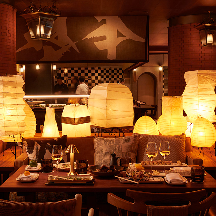 Une table avec du vin et de la nourriture AU Morimoto Bordeaux éclairée par des lanternes en papier