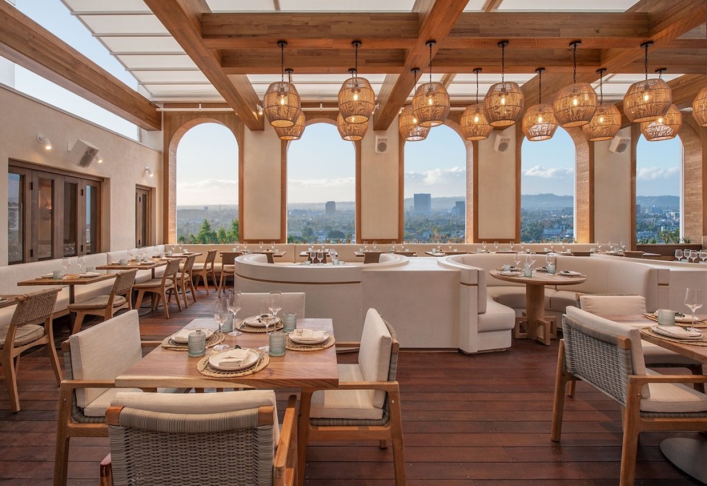 Airy rooftop restaurant Casa Madera at Mondrian Los Angeles with hanging wicker lights, large open windows and tables, chairs and couches