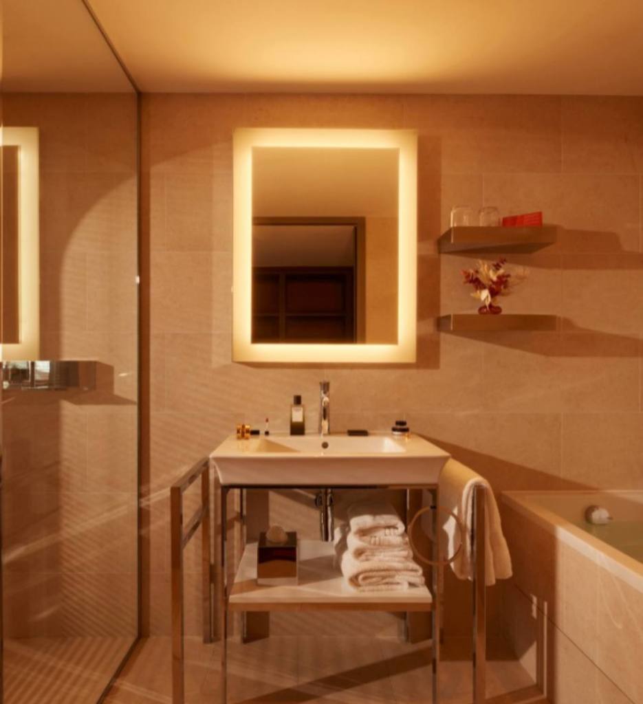 Cuarto de baño con un espejo iluminado, lavabo y bañera de la suite Mondrian de Mondrian Bordeaux Les Carmes 