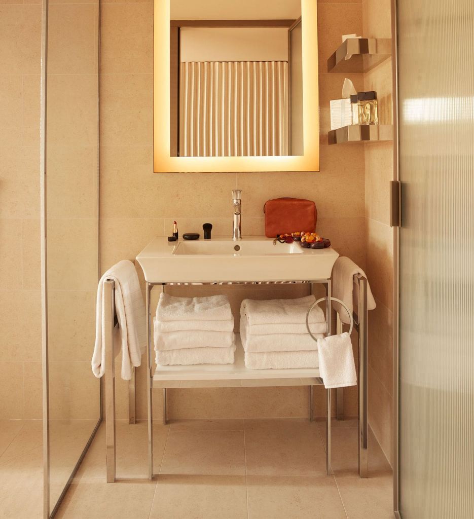 A modern bathroom featuring a sink, mirror, and towel rack.