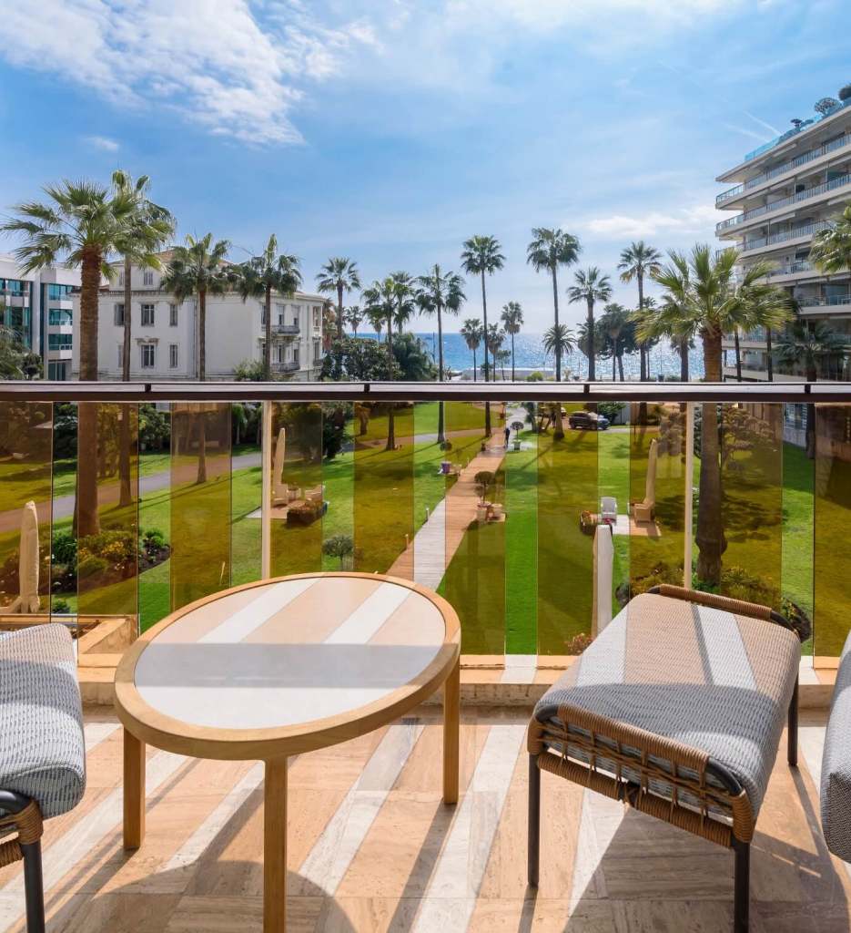 un balcon avec deux chaises et une petite table donnant sur un grand jardin