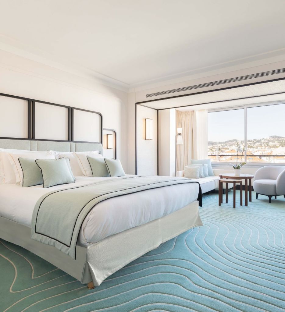 una preciosa habitación en el Mondrian Cannes con una alfombra azul y vistas a la ciudad