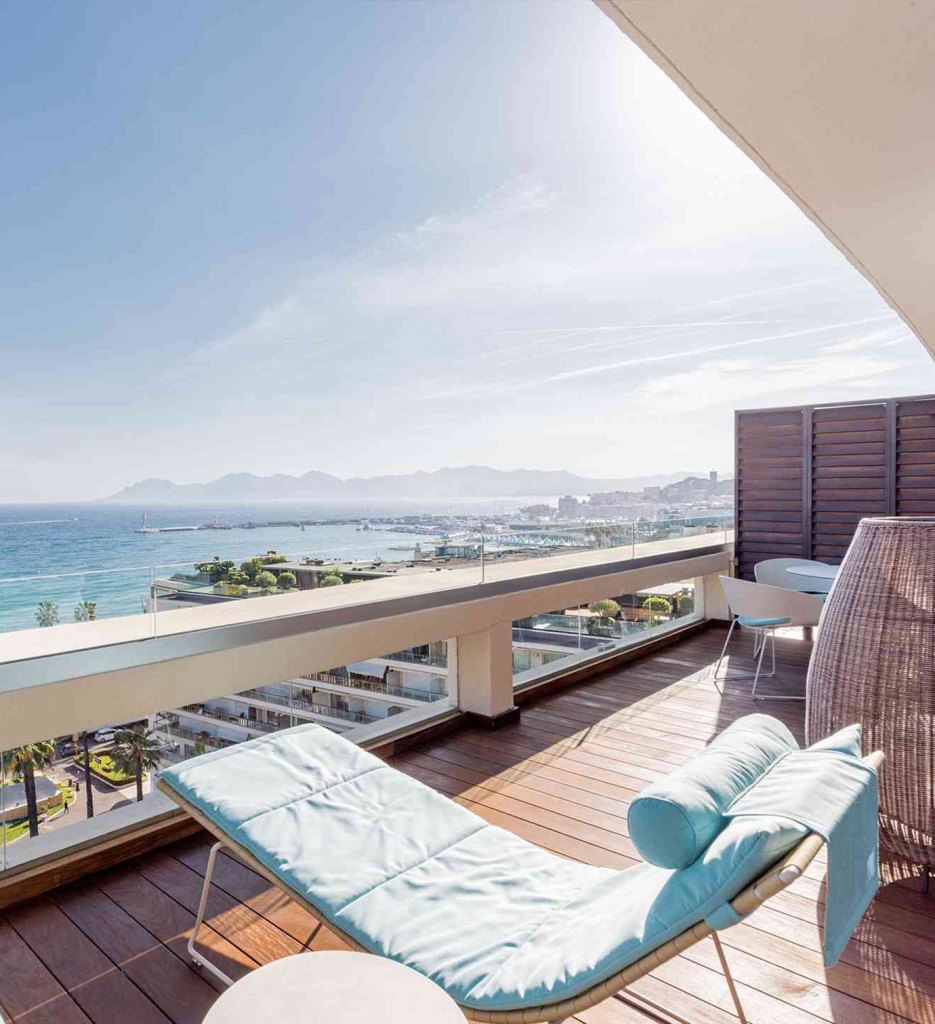 A serene ocean view from a balcony with comfortable lounge chairs.