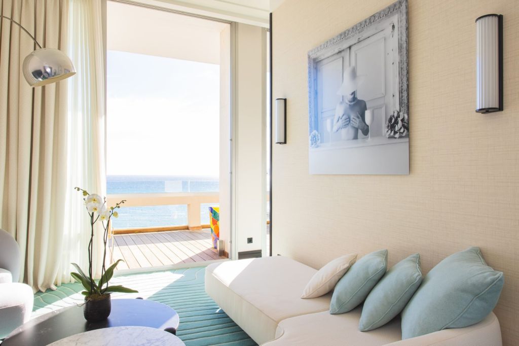 a suite at Mondrian Cannes with a white couch facing the floor to ceiling windows with views of the sea