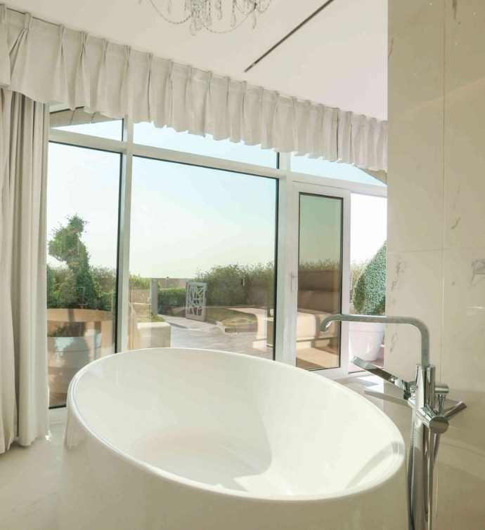 Giant bath tub in a bathroom with floor to ceiling windows with views