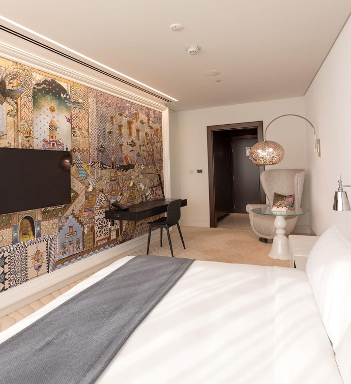 Chambre d'hôtel avec lit, téléviseur et fresque murale colorée 