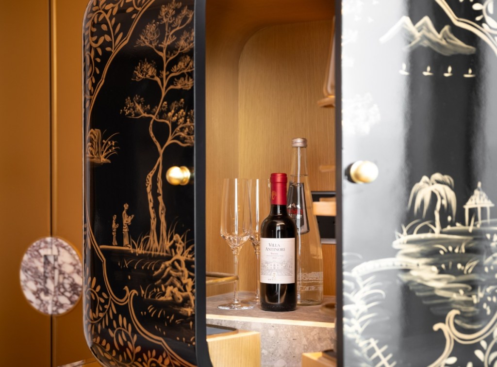 Intricately painted minibar with wine bottle, liquor bottle and glasses inside