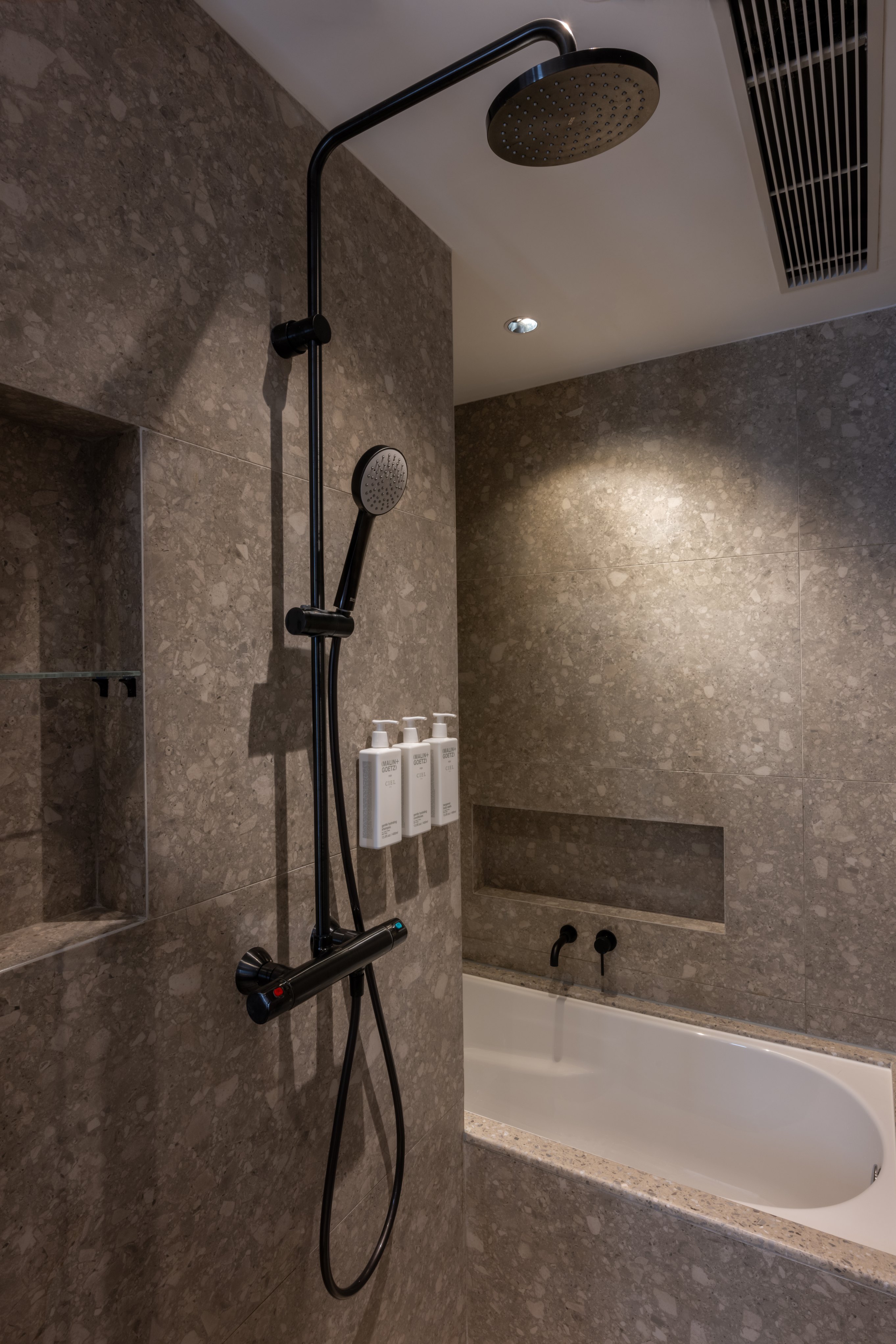 Modern shower with grey marble tiles and black overhead shower head