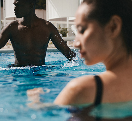 Man and woman standing up to their shoulders in a pool.