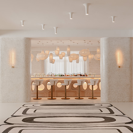 Beautiful modern white bar with white pendant lights, black and white geometric rug, and barstools.