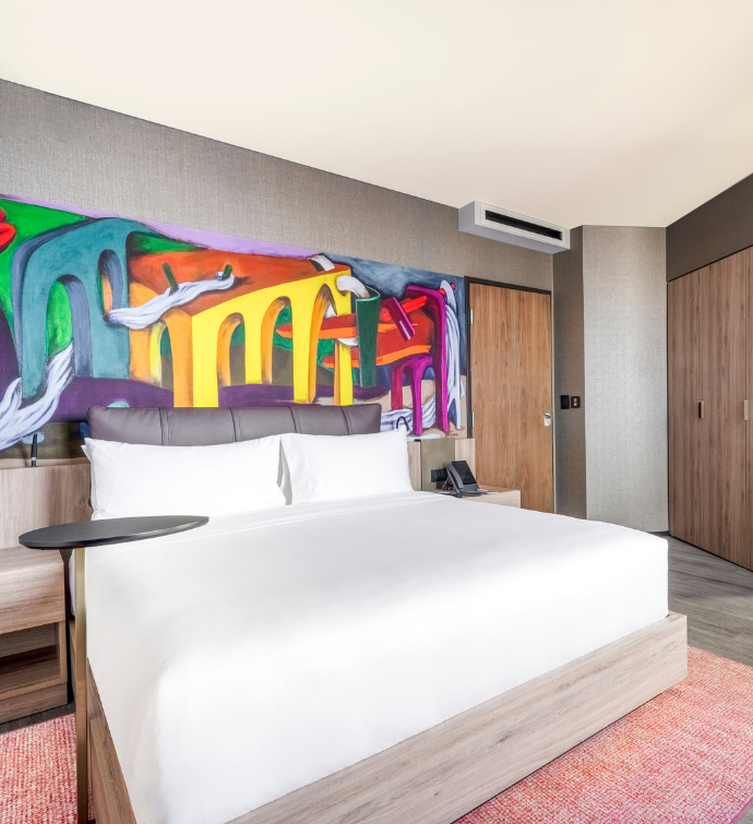 una suite en el Mondrian Mexico City Condesa con una cama y un mural gigante de colores en la pared