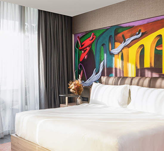 Hotel room at the Mondrian Mexico City Condesa with a bed and giant colorful wall mural