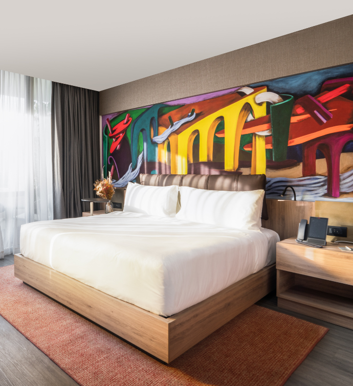 Hotel room at the Mondrian Mexico City Condesa with a bed and giant colorful wall mural