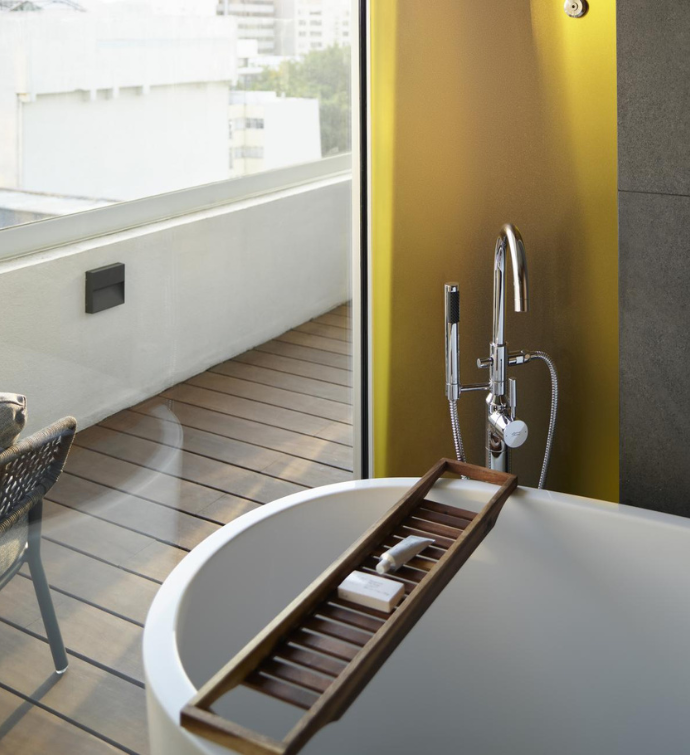 a large tub in a bathroom up against a window that leads to a terrace