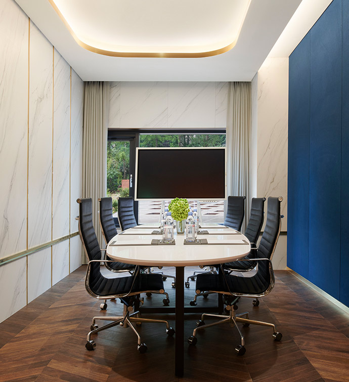 Boardroom with a long table, black chairs, a TV and a tray ceiling.
