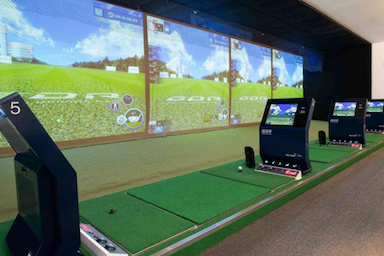 Indoor golf simulator with large screens and artificial green grass