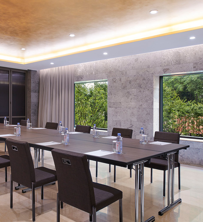 Conference room with long tables with black chairs, a gold tray ceiling and floor to ceiling windows.