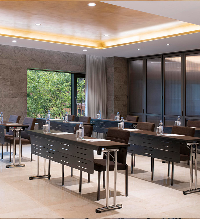 Conference room with long tables with black chairs, a gold tray ceiling and floor to ceiling windows.