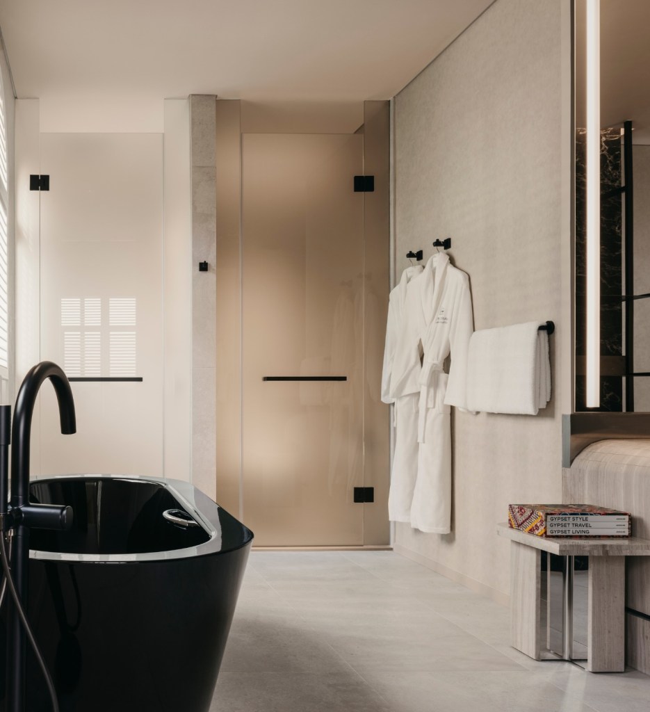 Bathroom with a large black tub and two robes hanging on the wall