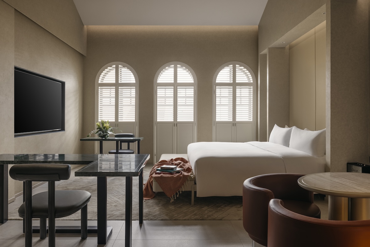 King sized bed with a bench at the end, and large windows with shutters