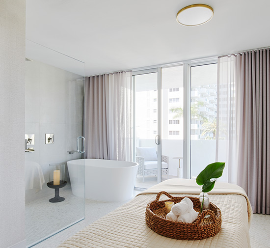 Luxurious spa room at Mondrian South Beach with a massage bed, tub and balcony.