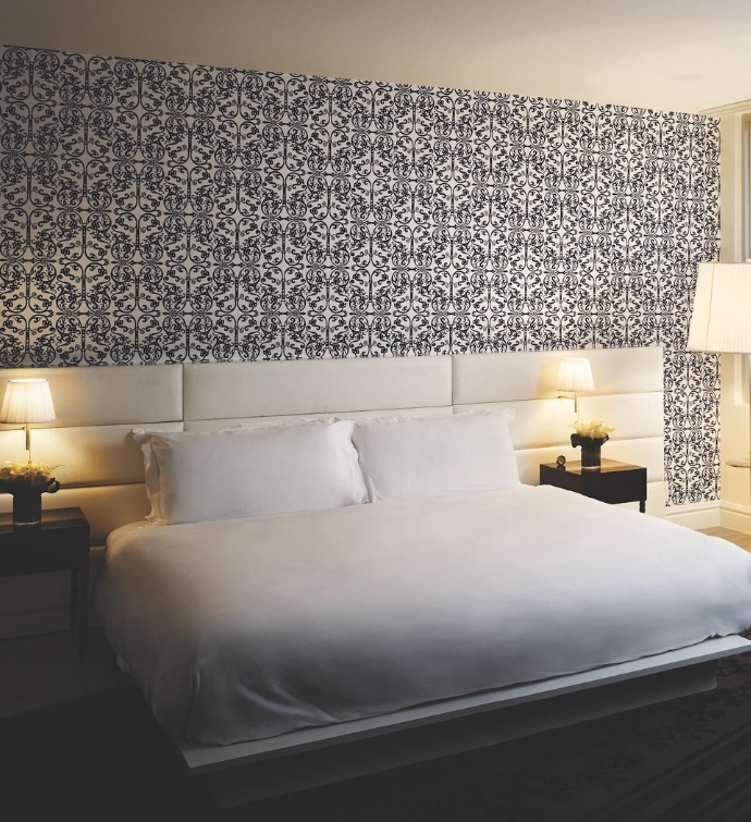 Large white bed with white headboard and blue patterned wallpaper