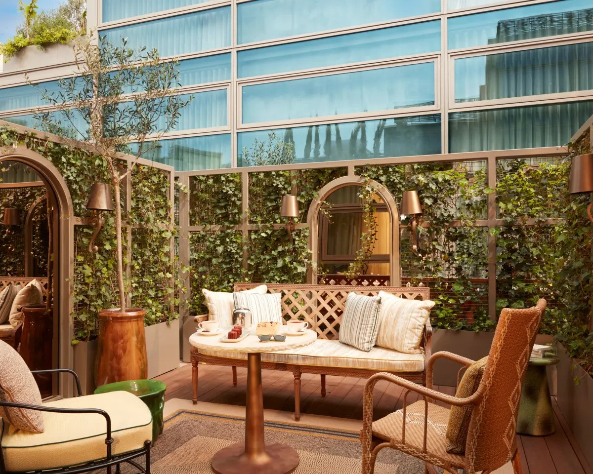 outdoor terrace with greenery, chairs, and a table