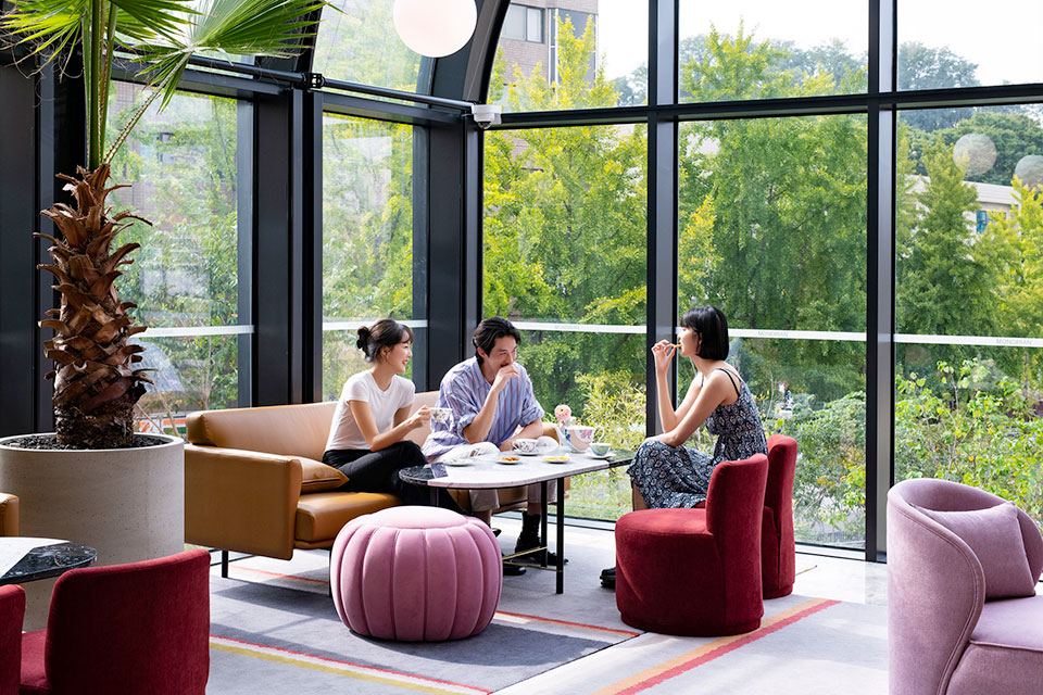 Two women and one man sit at a table in lounge chairs laughing