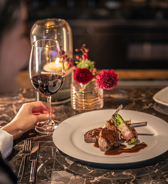 A dish of steak with a glass of wine