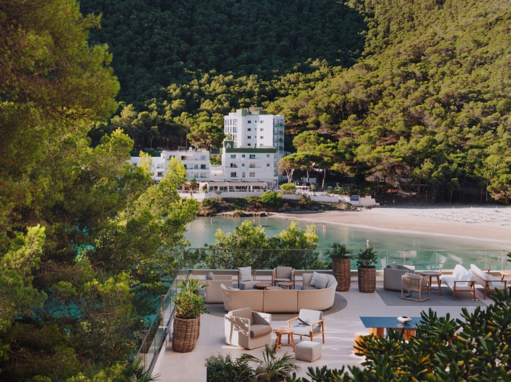 Aerial view of large patio with outdoor furniture looking over a beach with a white building in the background