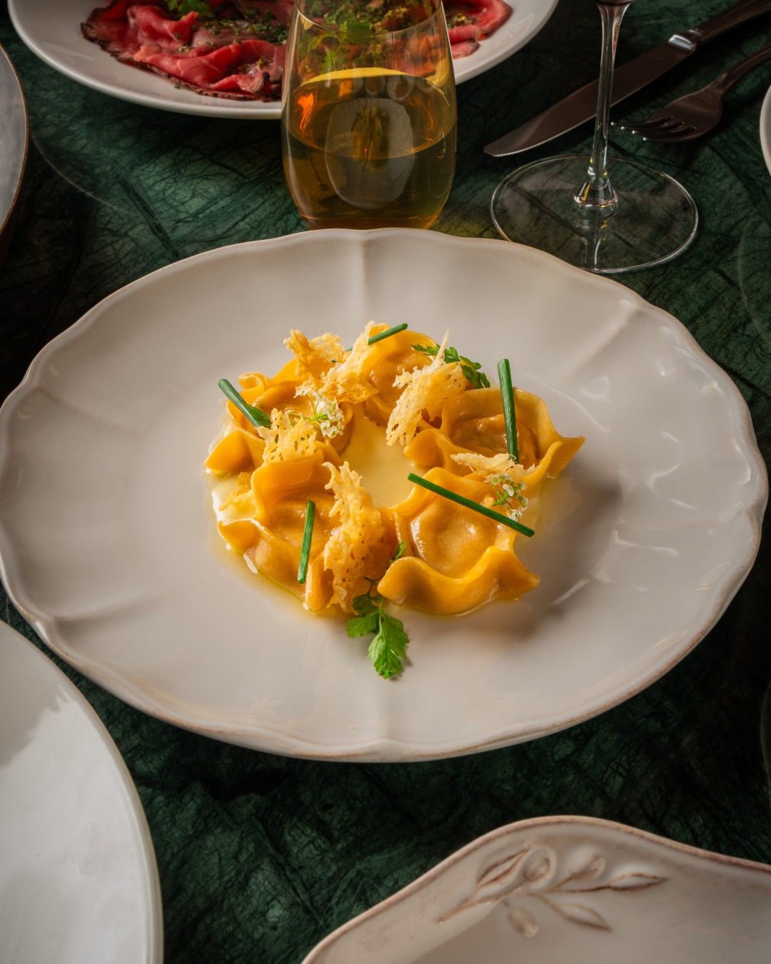 Oxtail Agnolotti with Capon Consomme & Black Truffle served on a white plate