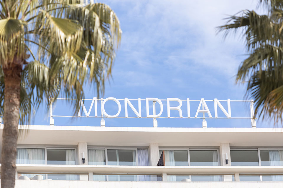 Cartel Mondrian en lo alto de Cannes, enmarcado por palmeras