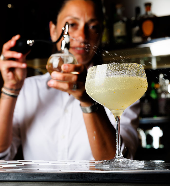 A bartender finishing a cocktail with a spray from an atomizer 