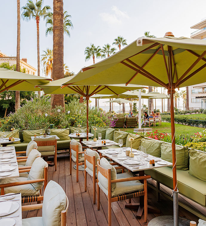 Outdoor dining patio with light green cushions and umbrellas