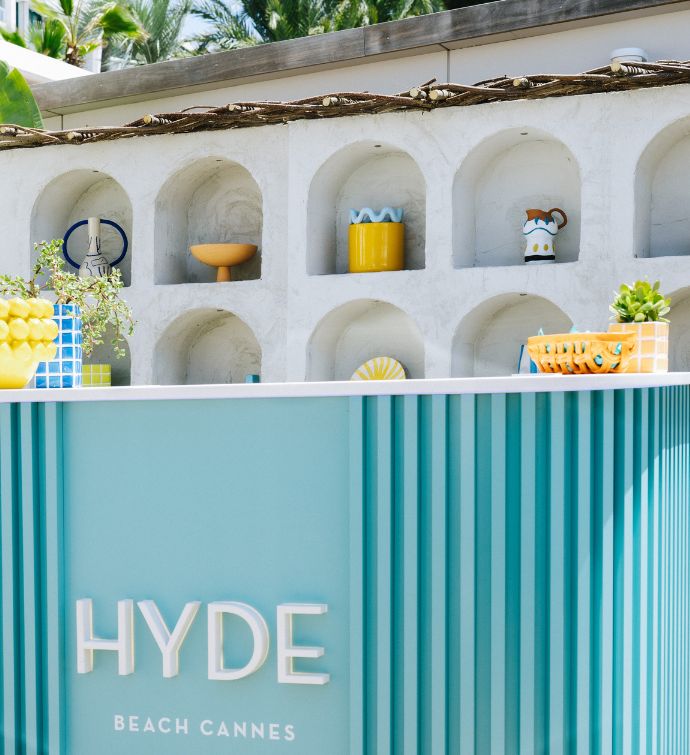 Bar extérieur bleu clair avec des murs blancs et des plantes en pot décorant le bar