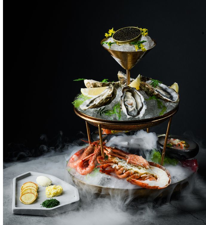 Seafood tower with oysters, caviar and lobster with smoke beneath it