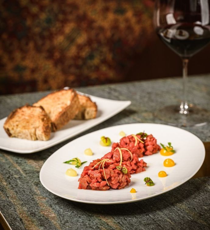 Plate of steak tartare with a side of bread, and glass of red wine