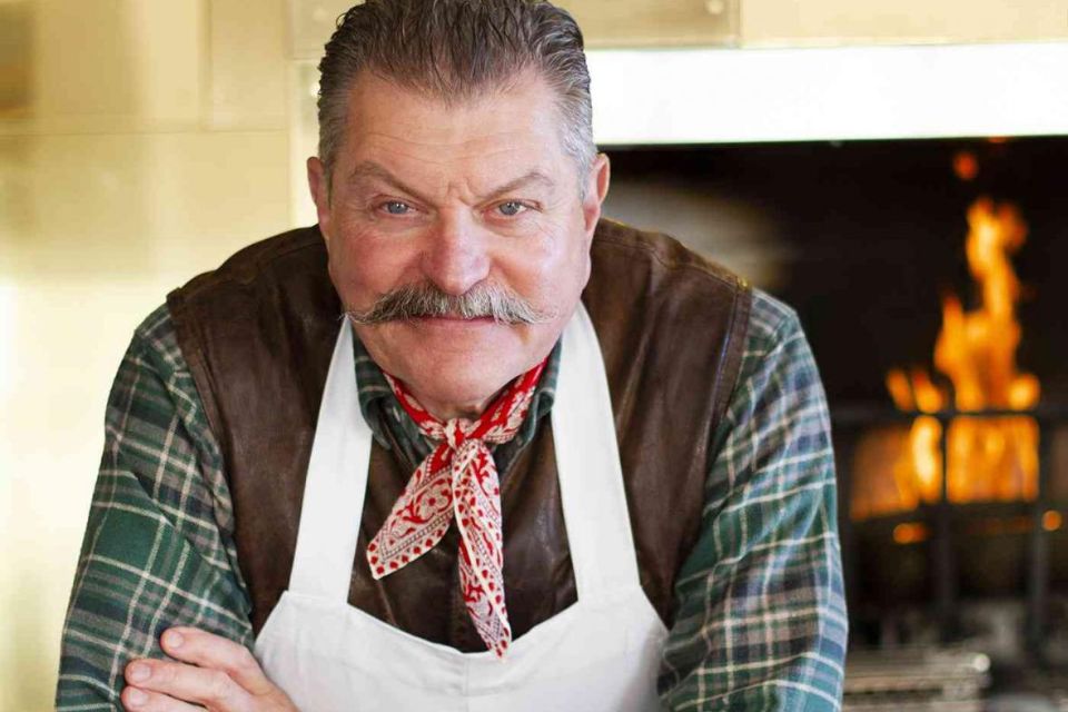 celebrity butcher Dario Cecchini with his arms crossed in front of a fire