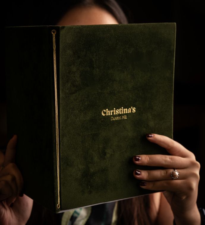 Woman holding a green velvet Christina's Duxton Hill menu