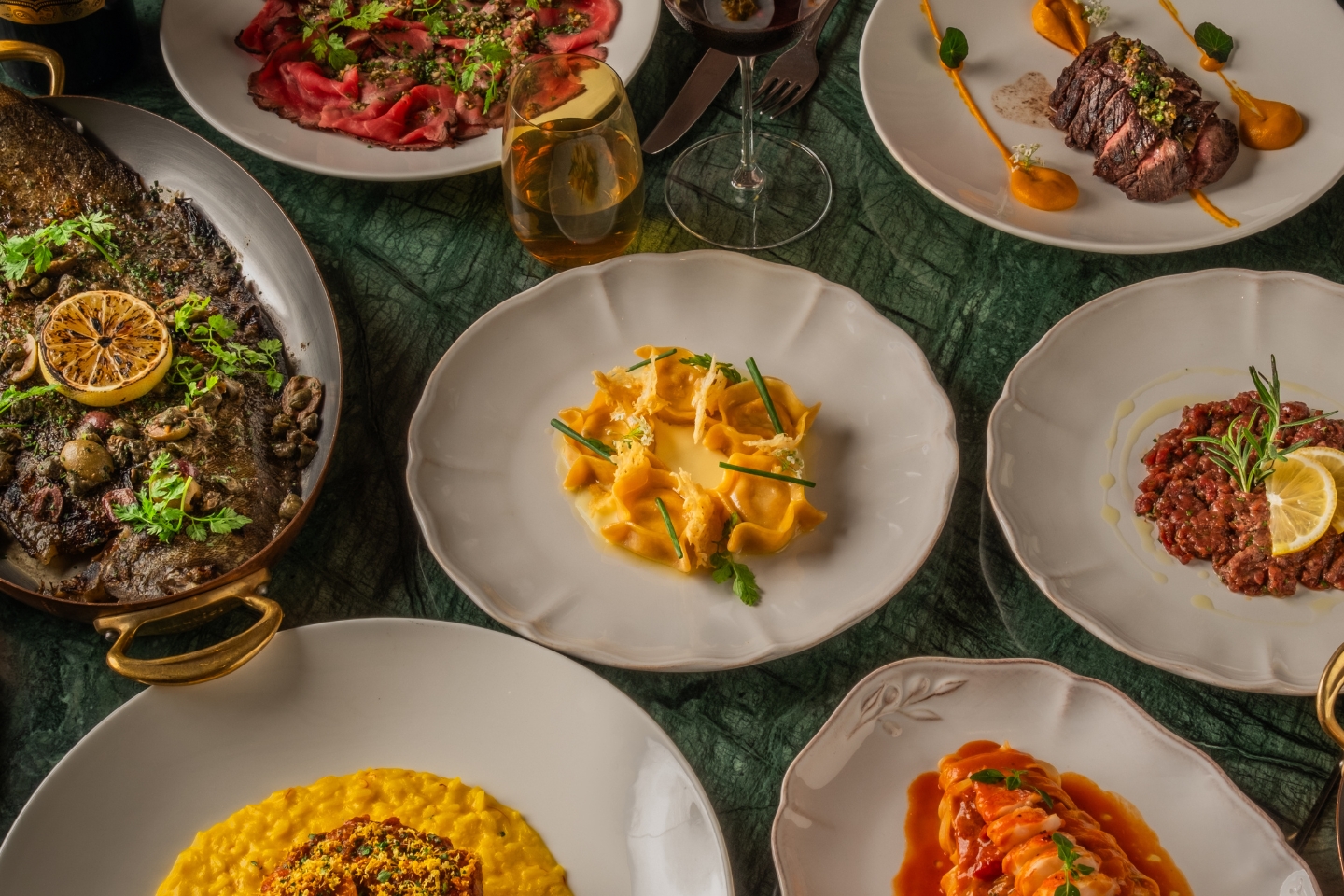 A full table of delicious italian food and flavours, with a glass of wine