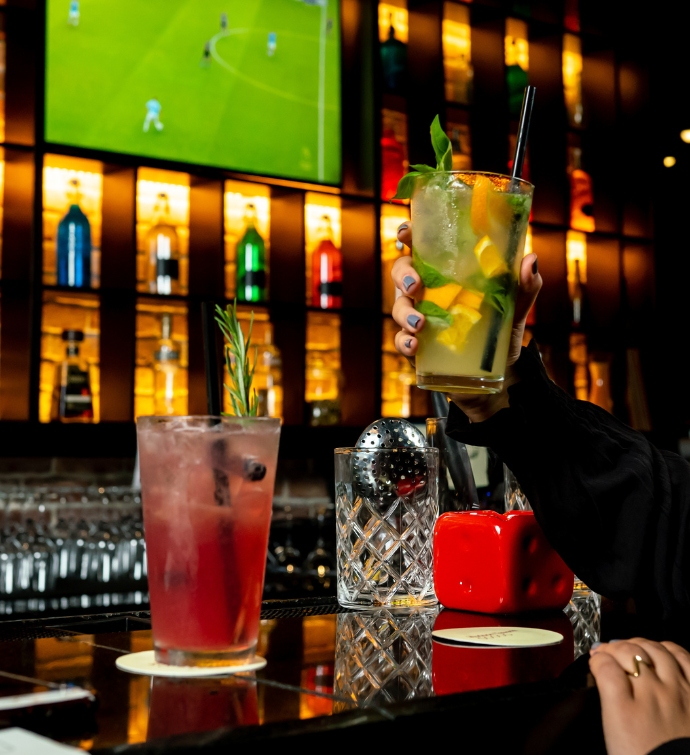 Hand holding a cocktail at the bar of Hudson Tavern Doha