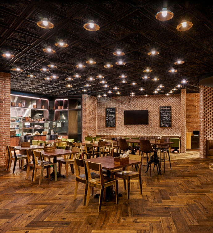 Interior de Hudson Tavern Doha con mesas de madera, sillas y una pizarra con el menú