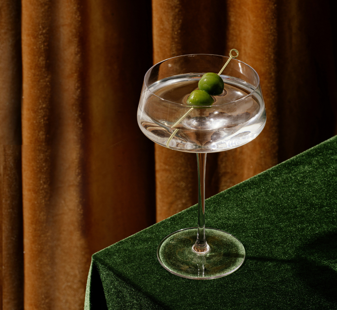 a glass of martini placed near the corner of a table
