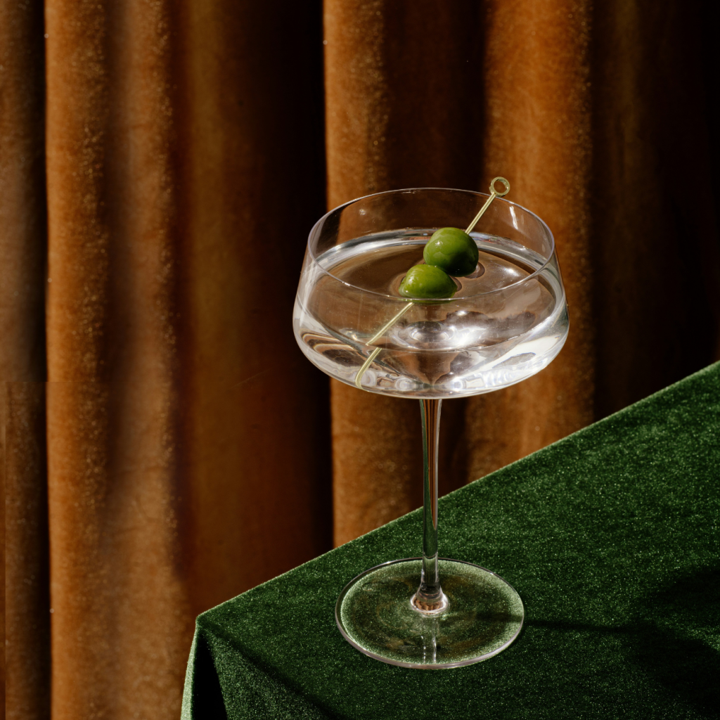 a glass of martini placed near the corner of a table